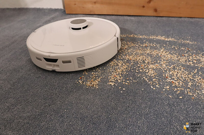 Der Roborock QRevo Curv saugt Haferflocken vom Teppichboden.